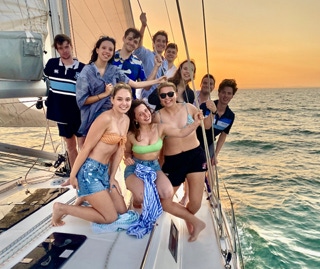 Friends posing for a photo on a sunset sail on a private yacht charter on Curlew Escape, Moreton Bay, Brisbane.