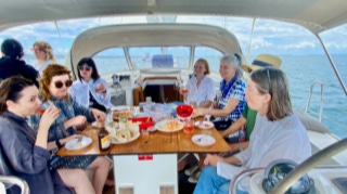 Guests dining around the cockpit table  on  Sailing Yacht Curlew Escape, available for private yacht charters on Moreton Bay, Brisbane.