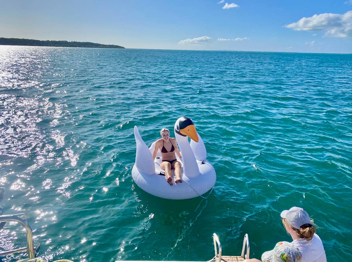 Birthday girl on a blow-up swan at Peel Island on sailing yacht Curlew Escape on a private yacht charter, Moreton Bay, Brisbane.