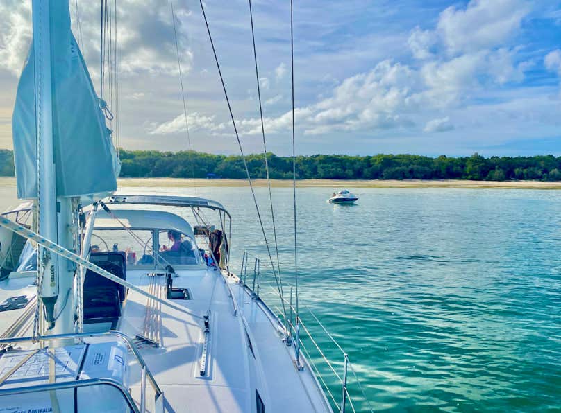 Friends enjoying lunch around the cockpit table while on a sailing charter in Moreton Bay.
